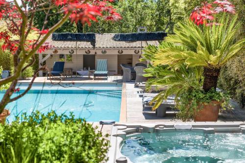 - une piscine avec un bain à remous et des palmiers dans l'établissement Superbe villa de plage avec piscine chauffée et jacuzzi proche des plages, à La Teste-de-Buch