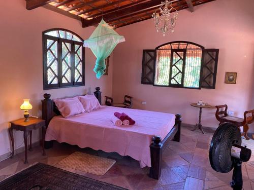 ein Schlafzimmer mit einem Bett mit rosa Laken und einem Kronleuchter in der Unterkunft Casa Paraiso in Paulista