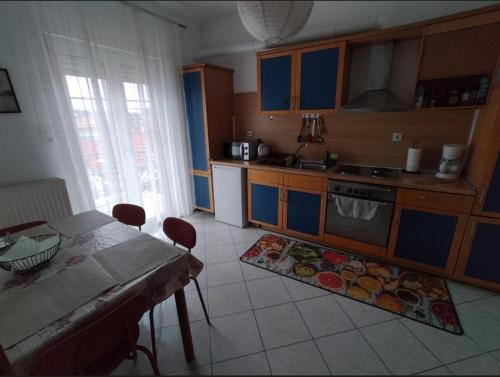 a kitchen with blue cabinets and a table with chairs at S.T Family Apartement in Kalabaka