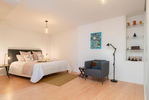 a white bedroom with a bed and a chair at HostWise - Artistic Escape with Modern Comfort in Vila Nova de Gaia