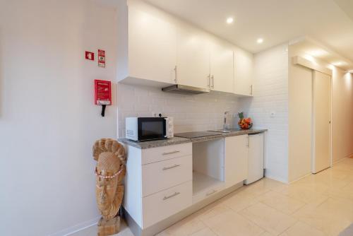 a kitchen with white cabinets and a microwave at HostWise - Artistic Escape with Modern Comfort in Vila Nova de Gaia
