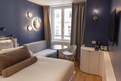 a hotel room with a bed and a table and a window at Hotel Leev Victoire & Spa in Paris