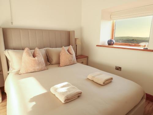 a bedroom with a bed with two towels on it at Cuddfan in Holyhead