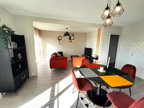 un salon avec une table et des chaises rouges dans l'établissement Ravissant appart-2chb-3 lits-wifi, à Châteauroux
