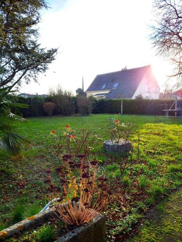 a garden with red flowers in a yard with a house at Jolie Maison 3 chb- 7 lits- jardin in Levroux