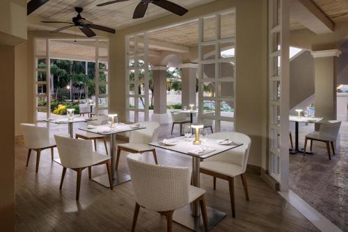 a restaurant with white tables and chairs and windows at Sandals Ochi Beach All Inclusive Resort - Couples Only in Ocho Rios