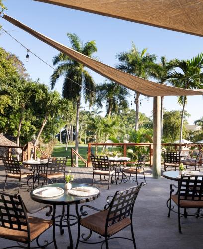 a patio with tables and chairs and palm trees at Sandals Ochi Beach All Inclusive Resort - Couples Only in Ocho Rios