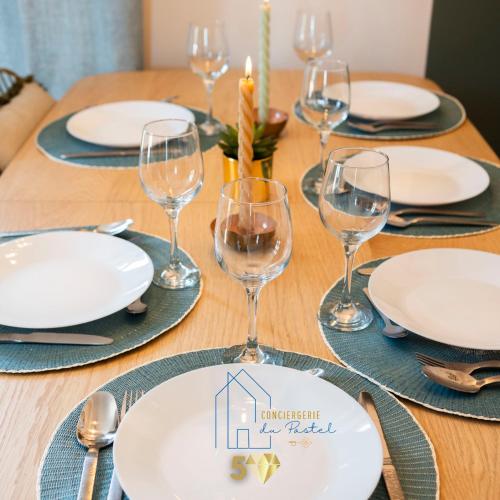 a wooden table with plates and wine glasses on it at Le Grillon de Pongo Elegant T2 avec balcons in Ax-les-Thermes