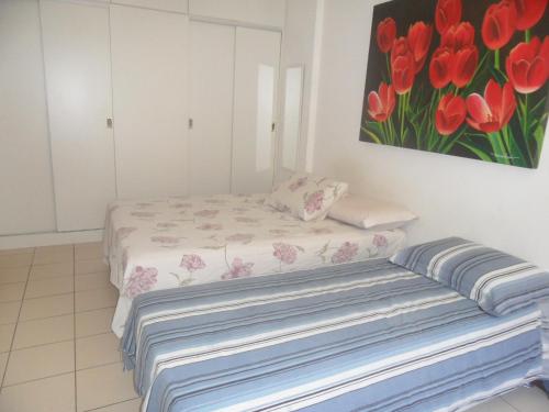 1 dormitorio con 1 cama y una pintura de tulipanes rojos en Barra Tropical Residence, en Salvador