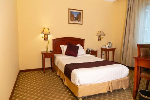 a bedroom with a bed and two tables and a desk at Dreamliner Hotel in Addis Ababa