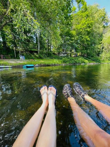 a person with their feet up in the water at Slumberland at the River's Edge in Pond Eddy