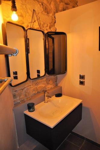 La salle de bains est pourvue d'un lavabo et de trois miroirs. dans l'établissement Domaine de l'héritage, à Grignan