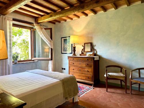 ein Schlafzimmer mit einem Bett, einem Stuhl und einem Fenster in der Unterkunft Tartagli Authentic Villa with Pool - a Fontanaro Property in Paciano