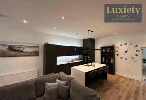 a living room with a couch and a clock on the wall at 2BR Flat By Luxiety Stays Short Lets & Serviced Accommodation Southend on sea With Free WiFi & Netflix in Southend-on-Sea
