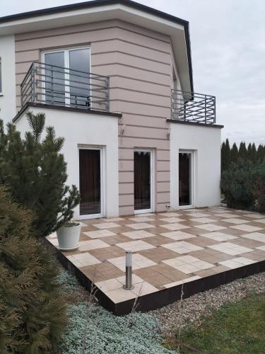 a house with a large patio in front of it at Dom za Tujami in Strykowo
