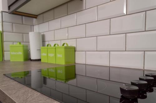 a white tiled wall with green boxes on it at Spacious Apt Dundee dockside 3-bedrooms fast Wi-Fi in Dundee