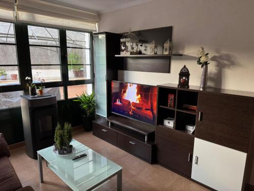 Una sala de estar con chimenea y televisión. en O Barqueiro- Fisher Village, en O Barqueiro