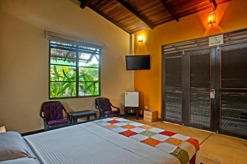 a bedroom with a bed and two chairs and a window at Hotel Amazon Bed And Breakfast in Leticia