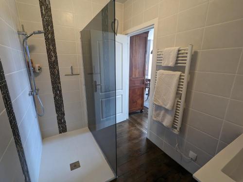 une salle de bain avec une douche avec une porte vitrée dans l'établissement La Maison Anglaise, à Monpazier