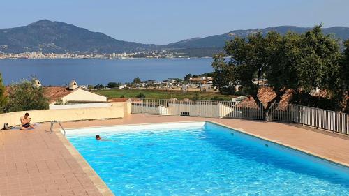 un homme assis dans une piscine à côté d'un lac dans l'établissement Appartement Studio Porticcio Paesolu 313, à Porticcio