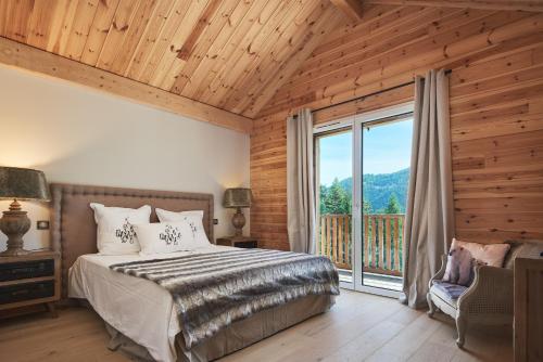 sypialnia z łóżkiem i dużym oknem w obiekcie Luxueux chalet avec terrasse Auron w mieście Saint-Étienne-de-Tinée