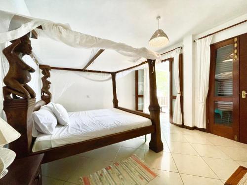 a bedroom with a canopy bed in a room at VITA'S BEACH House in Diani Beach