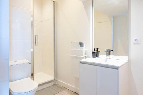 a white bathroom with a toilet and a sink at Petit appartement pour 2 à 3 personnes in Caen