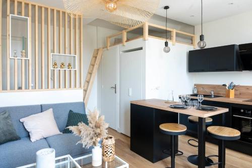 un salon avec un canapé bleu et une cuisine dans l'établissement Petit appartement pour 2 à 3 personnes, à Caen