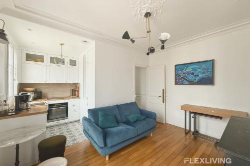 un salon avec un canapé bleu et une cuisine dans l'établissement Flexliving - T2 - Eugène Gibez, à Paris