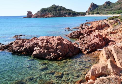 a group of rocks in the water near a beach at Baja Azzurra in Bari Sardo