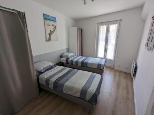deux lits dans une petite pièce avec une fenêtre dans l'établissement Appartement cœur de ville, à Bessan