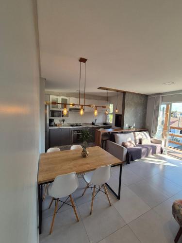 a kitchen and living room with a wooden table and chairs at Casa no segundo andar na Praia da Cal com ar e sacada in Torres
