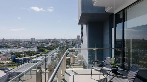a balcony with two chairs and a view of a city at Hotel Indigo Sydney Potts Point by IHG in Sydney
