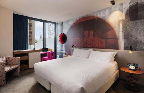 a bedroom with a large white bed and a chair at Hotel Indigo Sydney Potts Point by IHG in Sydney