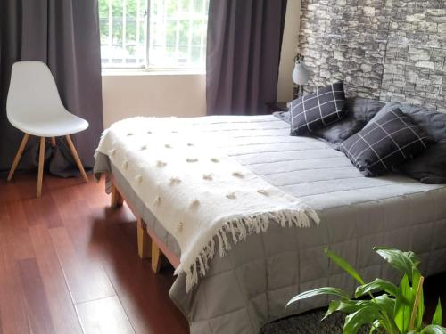 a bedroom with a bed and a white chair at Hostal Donde Gabriel in Chillán