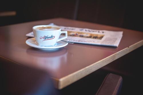 a cup of coffee and a newspaper on a table at Hotel Alexander in Wiesbaden