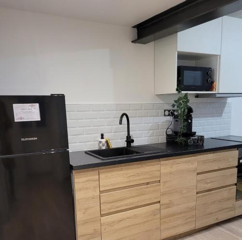 a kitchen with a black refrigerator and a sink at Appartement Moderne in Manosque
