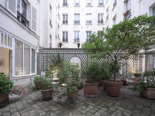 une cour avec des plantes en pot devant un bâtiment dans l'établissement Victoire I, à Paris