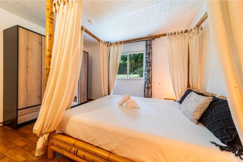 a bedroom with a bed with curtains and a window at Villa Horizon Bleu - Vue Mer & Piscine Chauffée in Le Tampon