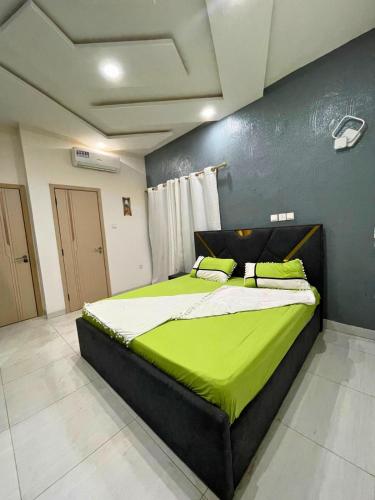 a bedroom with a large bed with green sheets at Landreas Complexe in Parakou