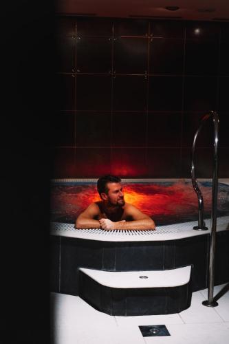 a man laying in a bathtub with at Pension Slunečnice & Panorama Restaurace Farma in Špindlerův Mlýn