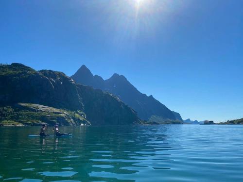 two people are sitting on a paddle board in the water at Surf Retreat Lofoten in Vestvågøya