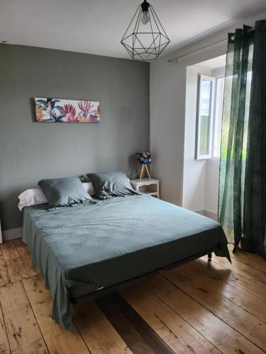 une chambre avec un grand lit avec une couverture verte dans l'établissement la maison de Léna, à La Bachellerie