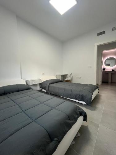 two beds in a white room with a window at Lujo en el centro con parking privado 3 in Adra