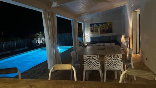 a dining room with a table and chairs and a pool at La Villa Miranda Meublé de Tourisme 4 * in Saint-Gilles les Bains
