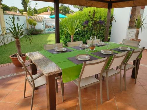 a table with chairs and a green table cloth at Villa con piscina junto a la playa in Roche
