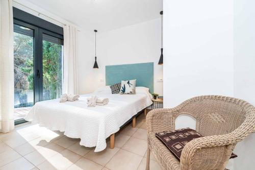 a white bedroom with a bed and a chair at Villa Abeto in El Tosalet