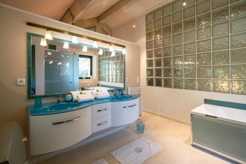 une salle de bain avec deux lavabos et un grand miroir dans l'établissement Mas des Fontètes, à Fontvieille