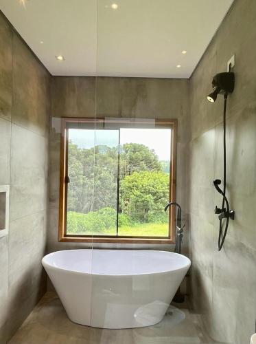 a bath tub in a bathroom with a window at Casa Brandão Pousada in Bueno Brandão
