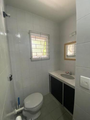a white bathroom with a toilet and a sink at Sobrado Veneza Caiobá 2 Quartos in Matinhos